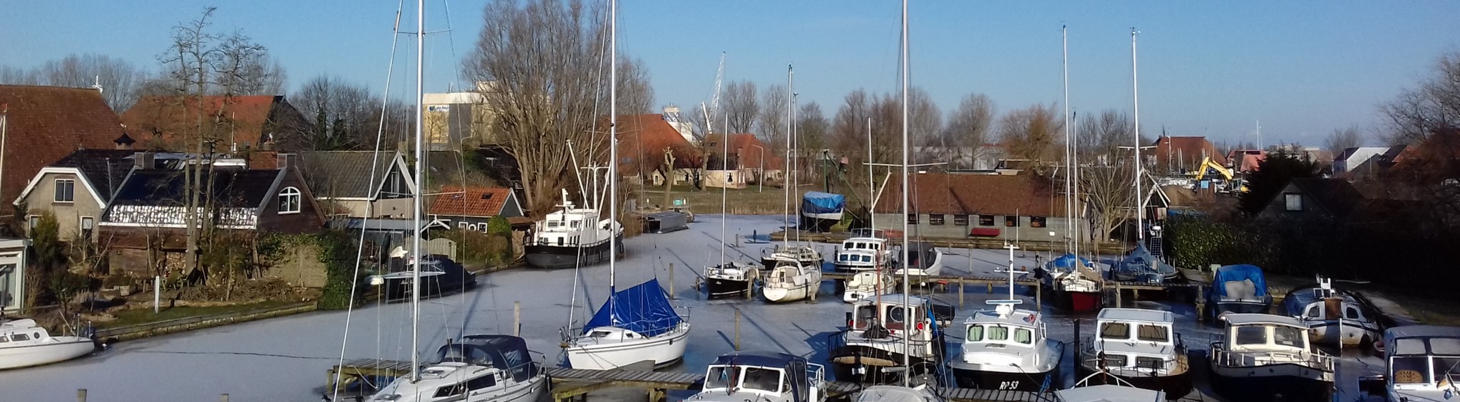 De haven dichtgevroren onder een strakblauwe hemel, met de boten vast in het ijs