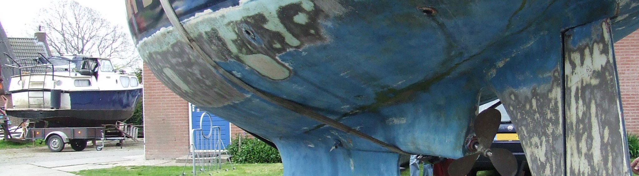 Een casco uit het water op een bok, met de schroef en het roer vrij, tijdens het reinigen van het onderwaterschip
